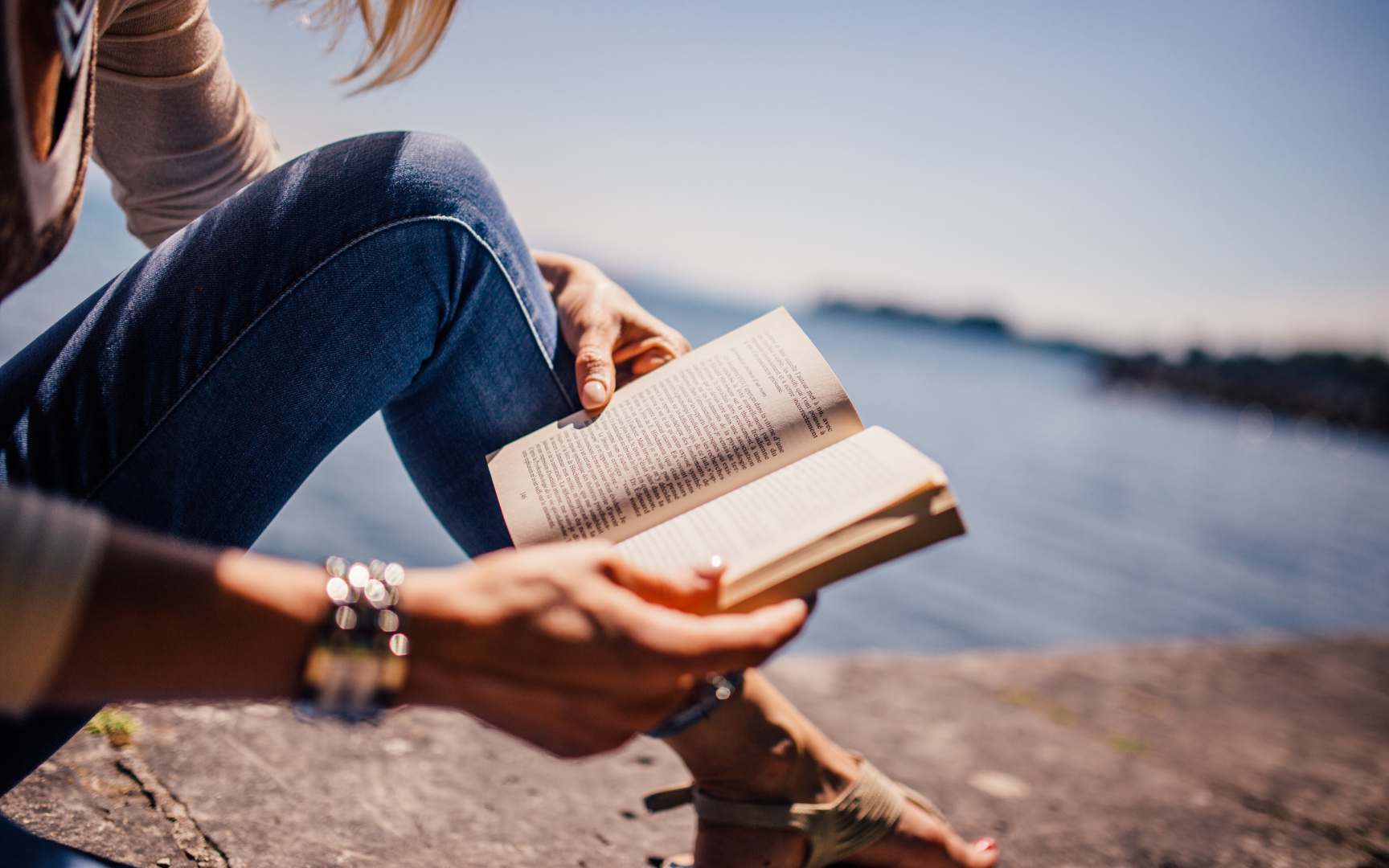 Kvinna som sitter på en klippa och läser under en stressfri semester